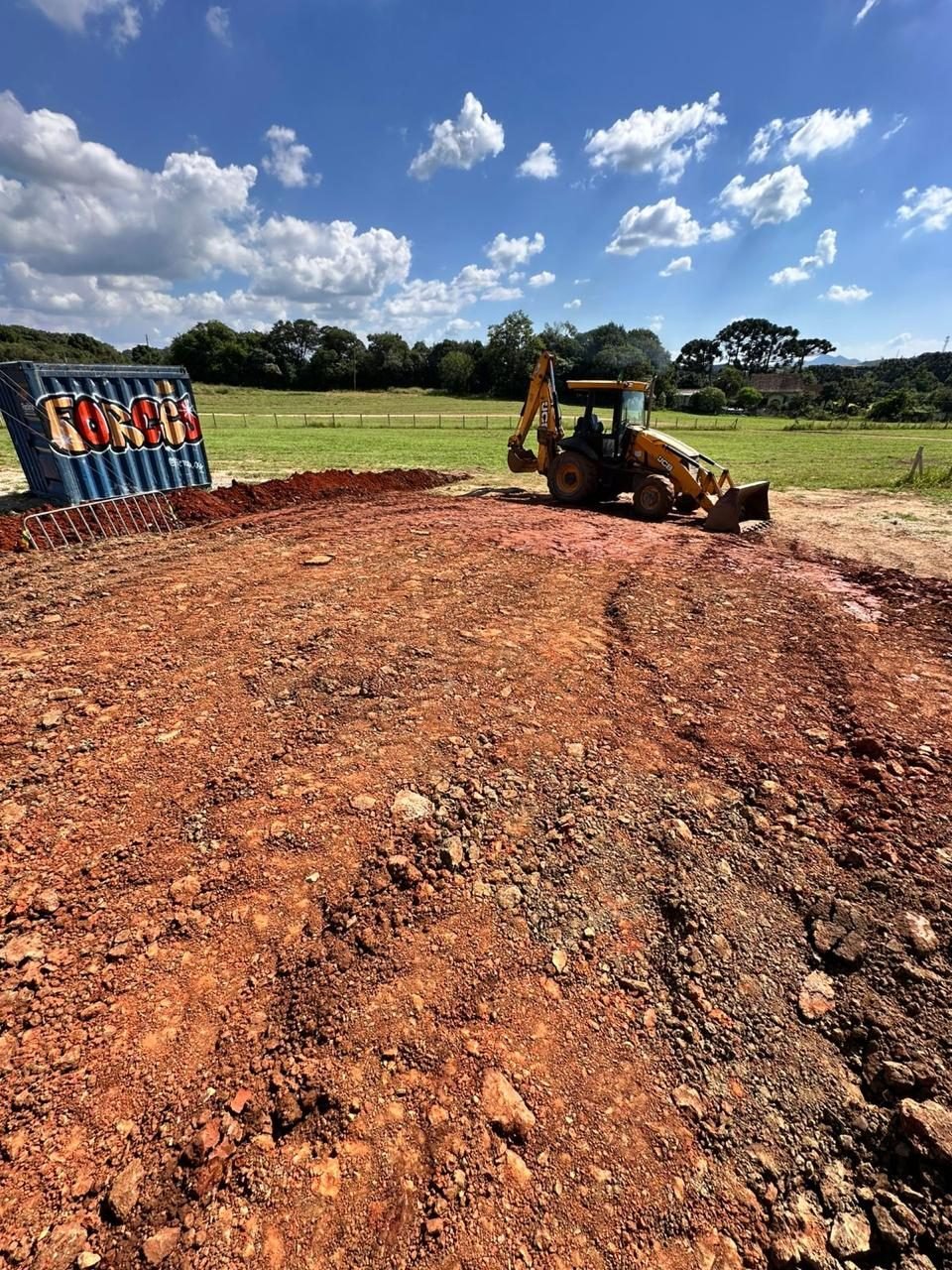 Retroescavadeira JCB preparando terreno para obra