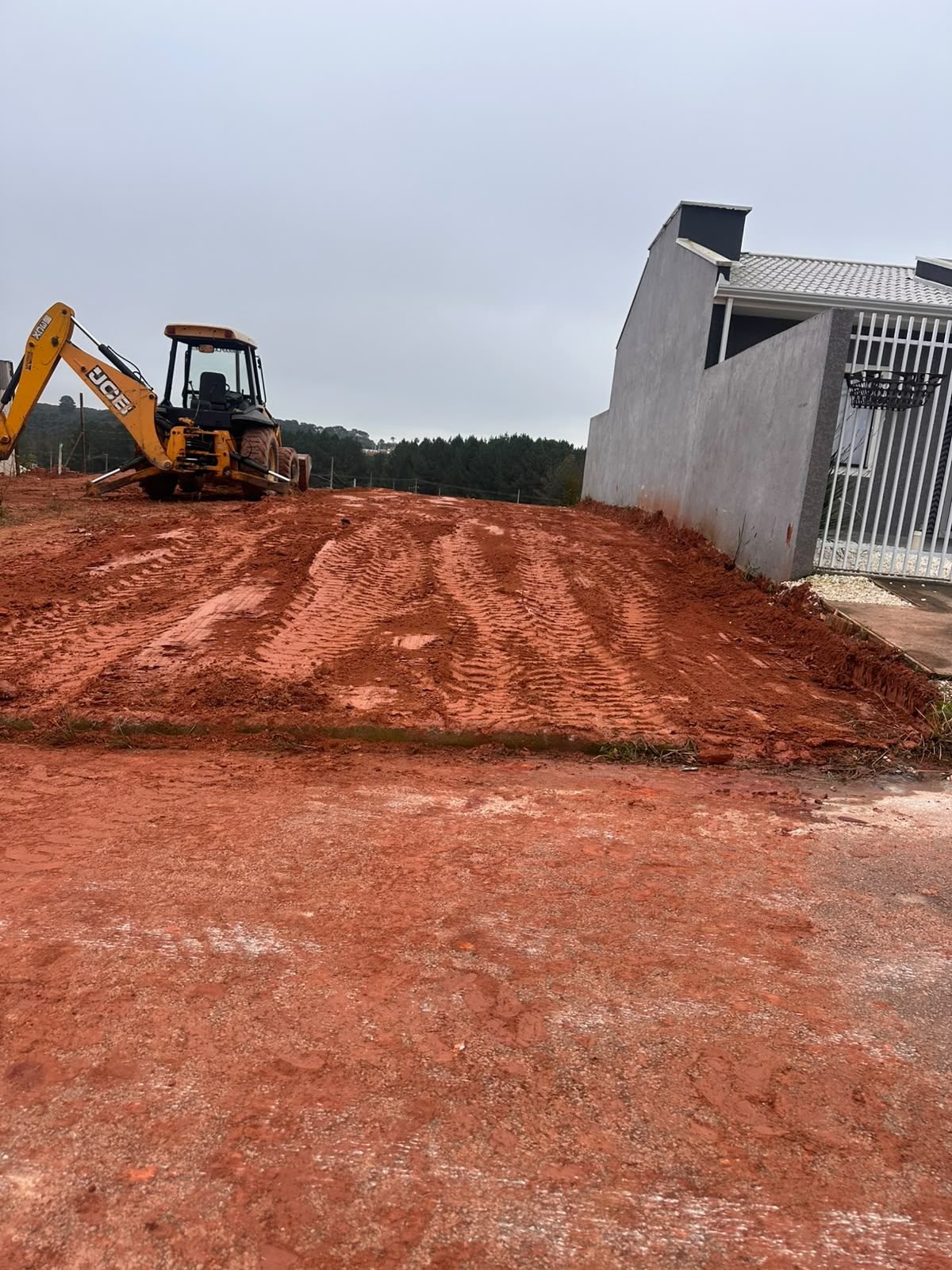 Terreno nivelado ao lado de residência pronta, com retroescavadeira JCB